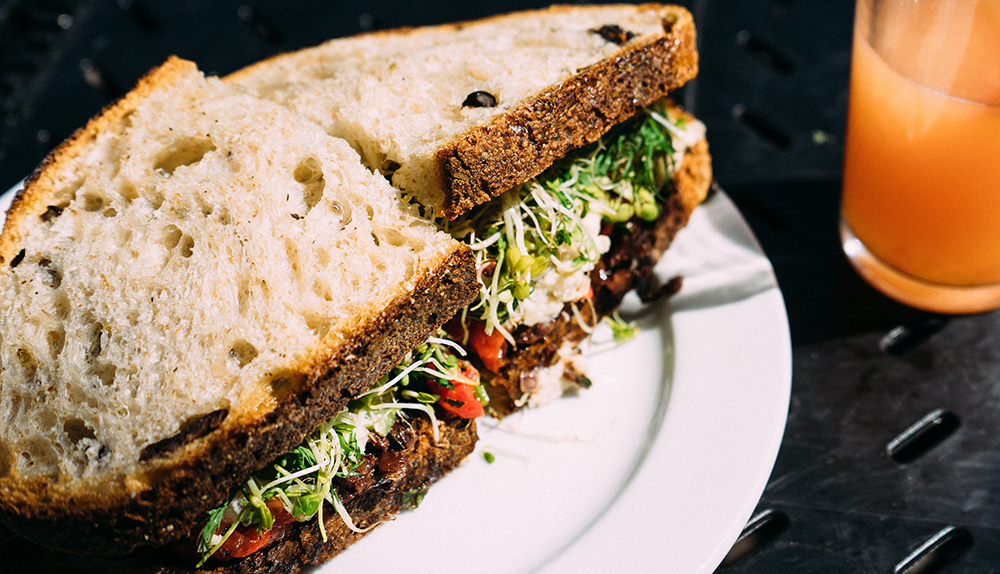 bread-food-salad-sandwich-healthy-austin-restaurants A sandwich alongside an orange drink