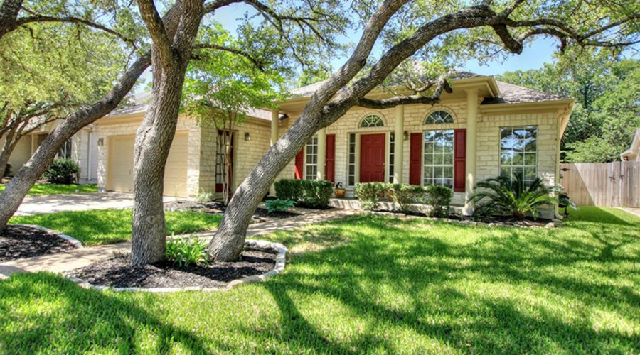 A home with bushes and trees in the front yard