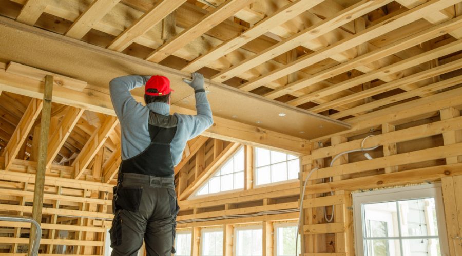A builder working on the wooden frame of a new house