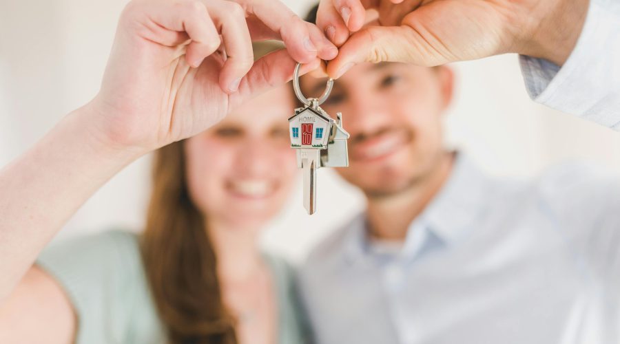 a millennial couple holds up the keys to their new home